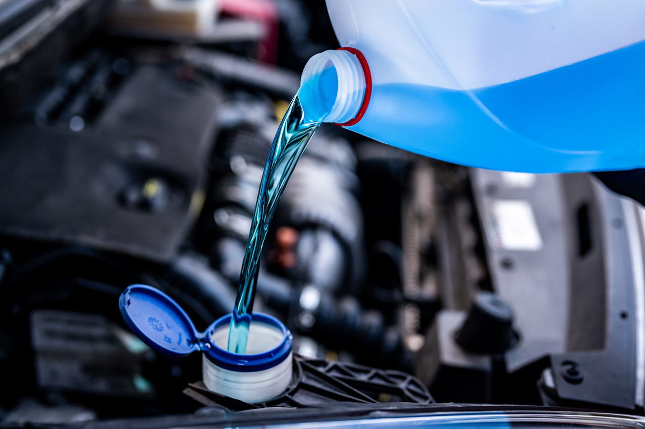 Mazda service technician refilling windshield wiper fluid