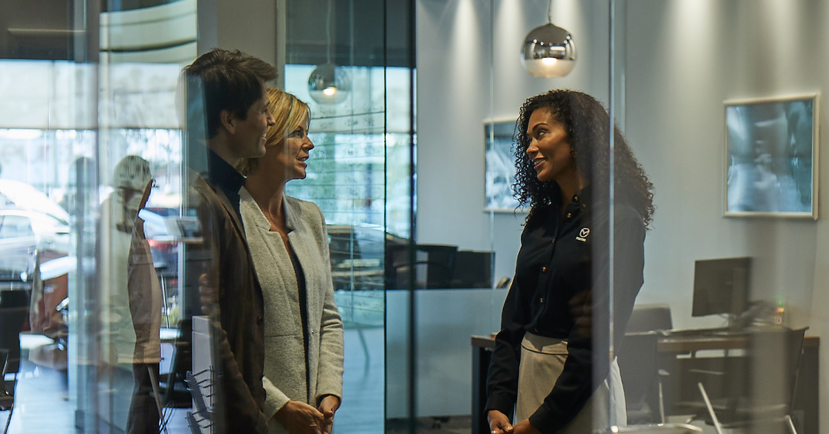 Customers speaking with salesperson at a Mazda dealership