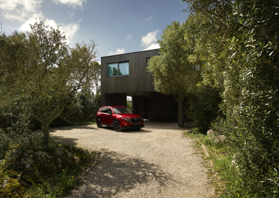 Red 2026 Mazda CX 5 parked outside a modern home available at Route Mazda.