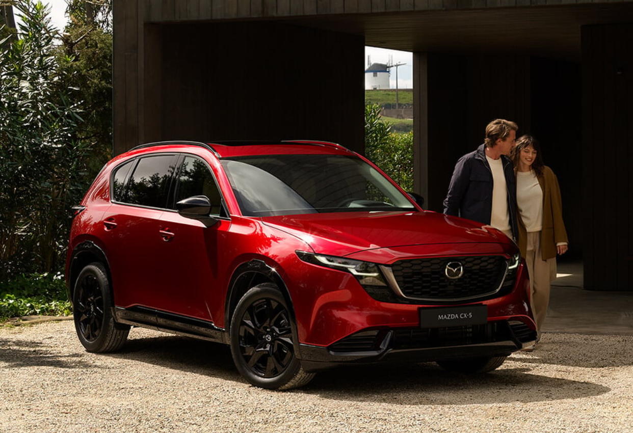 Red 2026 CX-5 Mazda CX-5 SUV parked outside with couple standing nearby at Route 9 Mazda.